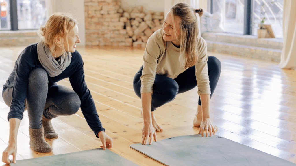 Zwei Frauen rollen ihre Yogamatten aus und praktizieren Yoga für mentale Gesundheit